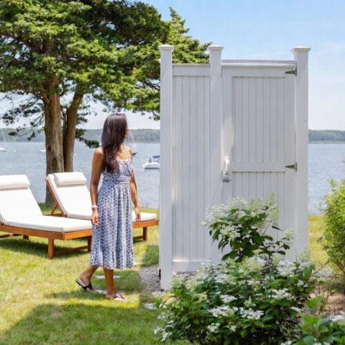 backyard view of white outdoor shower design in summer time