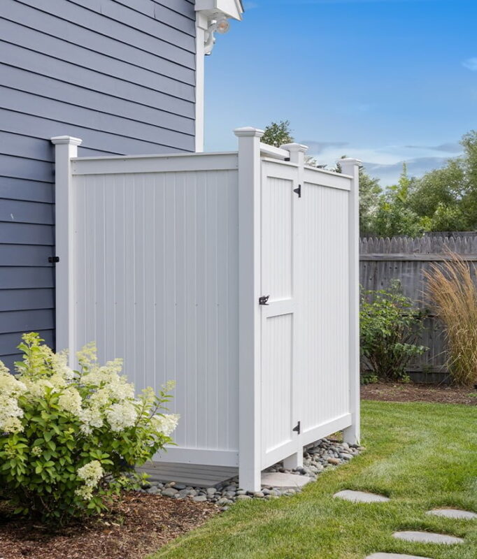 outdoor shower set against house next to plant