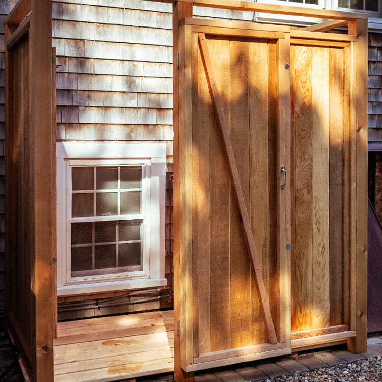 cedar outside shower enclosure shown against a house
